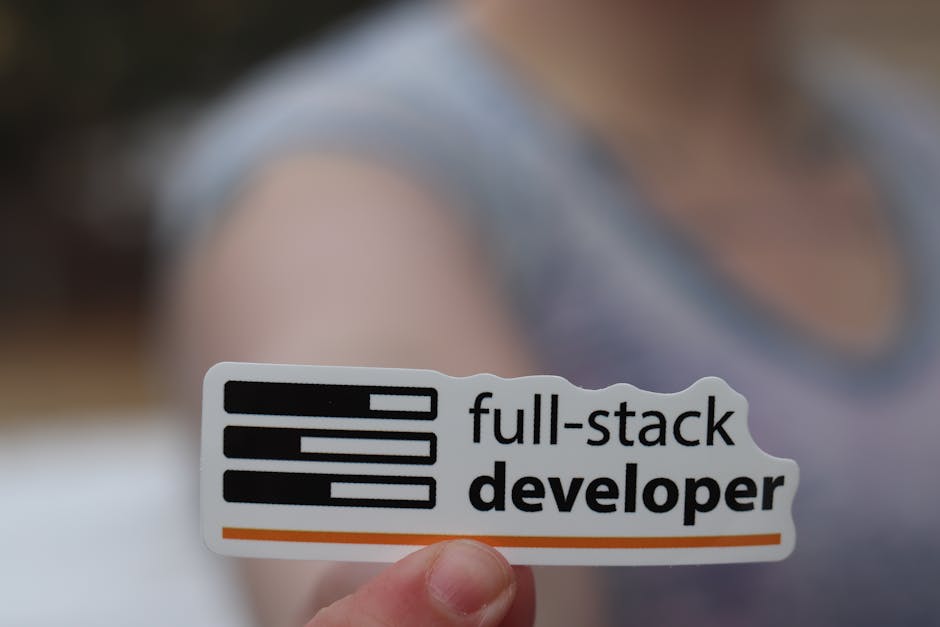 A close-up view of a person's hand holding a white rectangular sticker with black text and graphics. The sticker displays three horizontal black bars stacked vertically on the left, with varying lengt